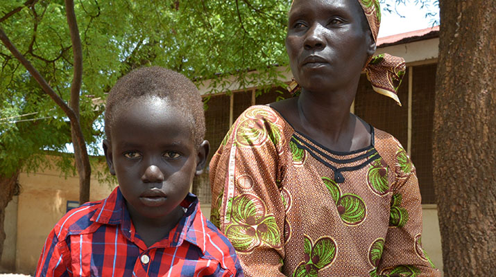 [Yohana sits with his mother near a pharmacy at Al Sabah Children's Hospital in Juba, South Sudan.] {Photo Credit: Abraham Ayuen/MSH}