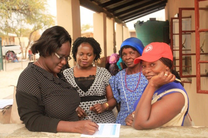 [Pehovelo Ndahangoudja (left), a registered nurse documents feedback on CBART from Know your Status CASG member Julia Sheepo (2nd from right) and leader Marian Ndahafo Lilonga (right) at Ndamono clinic, Onandjokwe district.] {Photo credit: Stanley Stephanus for SIAPS Namibia}