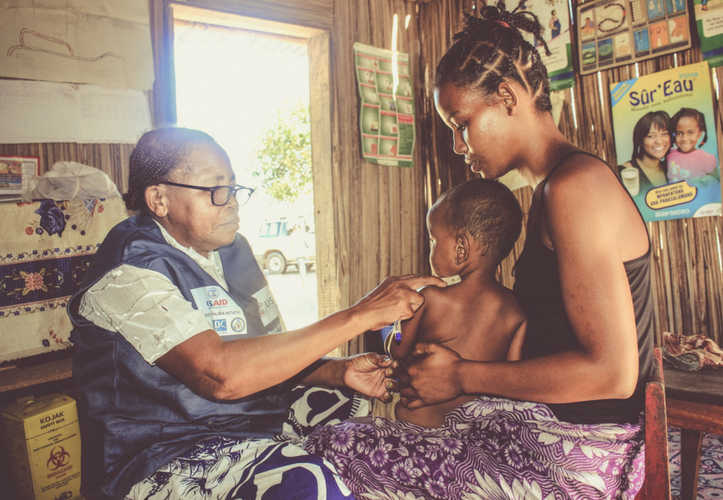 [A Community Health Volunteers monitors the growth of child during a home visit.]