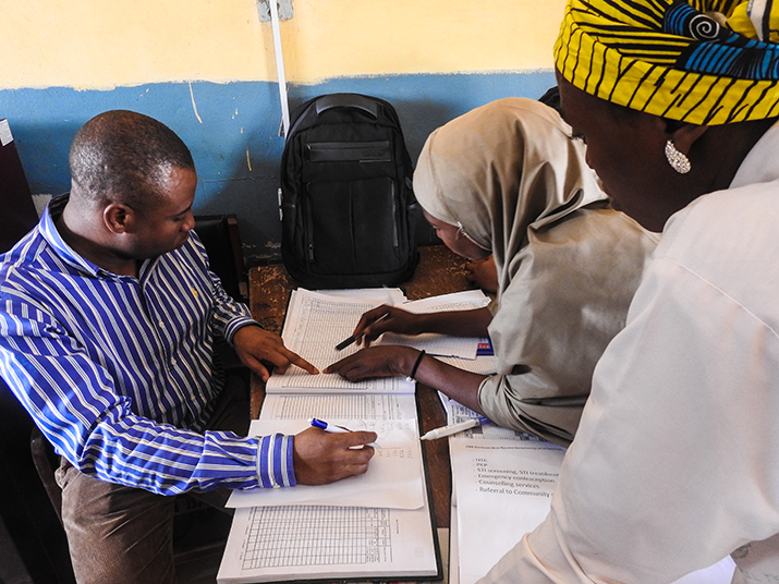 [MSH staff member, Christopher Ogar, verifies information from a HIV testing services register with facility staff at  General Hospital Suleija in Niger state, Nigeria.] {Photo credit: Aor Ikyaabo/MSH}