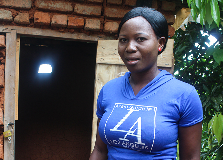 [Faliya Mungwala shows off one of the latrines that she constructed.]