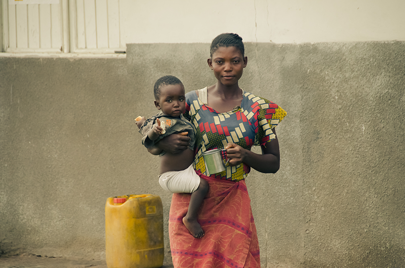 {Eine Mutter und ein Kind warten vor einer Klinik am Stadtrand von Mbuji Mayi, Demokratische Republik Kongo. Bildnachweis: Warren Zelman}