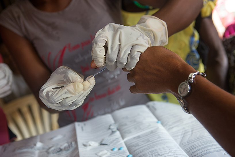 [Um voluntário da comunidade fornece testes de HIV gratuitos em um mercado local em Eyokponung, Nigéria. Crédito da foto: Gwenn Dubourthournieu / MSH]