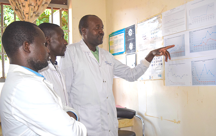 [Laboratory technician, Samuel Oule, discusses laboratory data with the facility in-charge, Dr. Denis Omiat, at Apapai Health Centre IV.] {Photo credit: MSH staff}