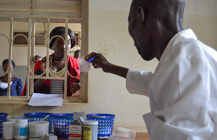 [A pharmacist dispenses medicines to a patient at Arua Regional Referral Hospital.] {Photo credit: UHSC/MSH staff}