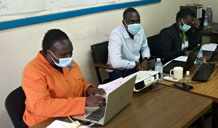 [National Medical Stores staff undergo a practical session on processing of orders for COVID-19 emergency supplies using the eELMIS with a trainer from MSH/UHSC.] {Photo credit MSH staff}