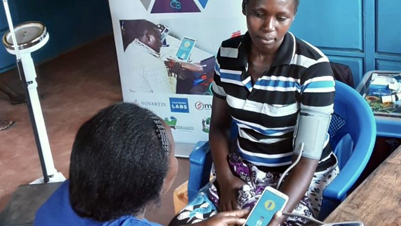 [Un trabajador de la salud en el condado de Kakamega, Kenia, mide y registra la presión arterial de un paciente utilizando un sistema de salud digital introducido por Afya Dumu. Crédito de la foto: Richard Nyakundi, Medtronic Labs]