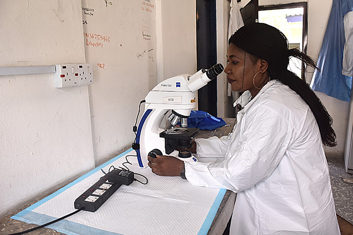 [Un científico de laboratorio usa un microscopio para una prueba de malaria en un centro de salud respaldado por PMI-S. Crédito de la foto Oluwatobiloba Akerele / MSH]