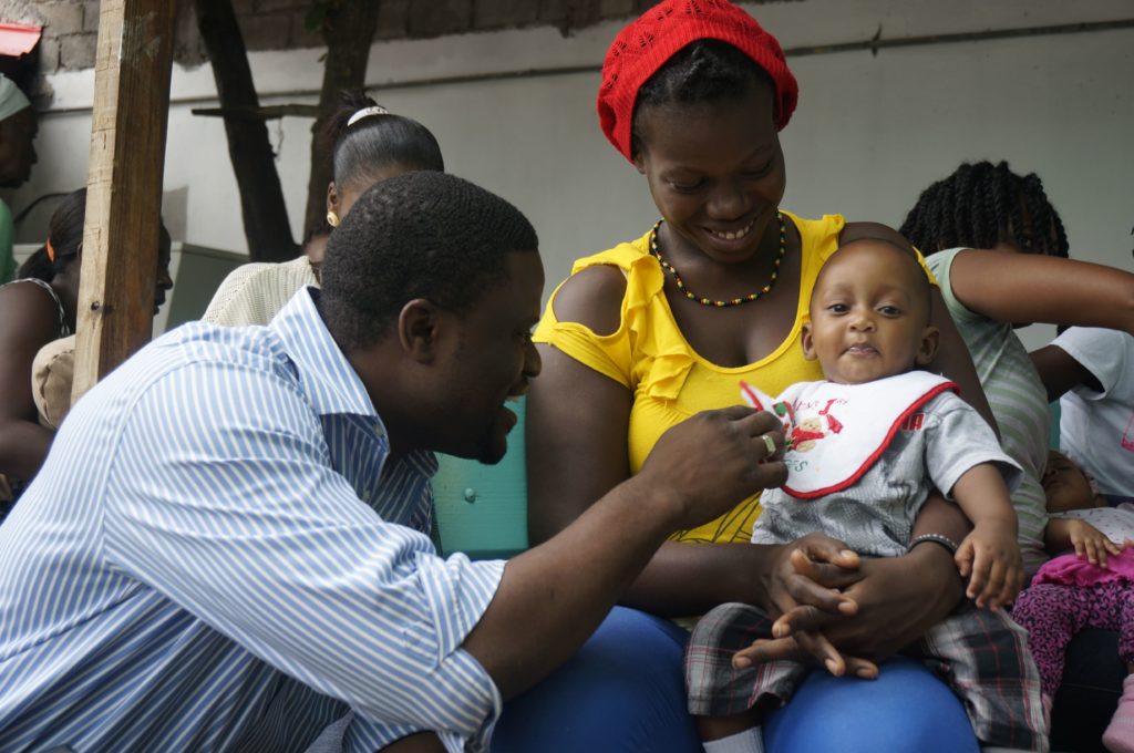 Un médico de la clínica se hace amigo de un joven que espera la vacunación en la clínica Delma 75 cerca de Port-au-Prince, Haití, crédito de la foto de Carole Douglis.