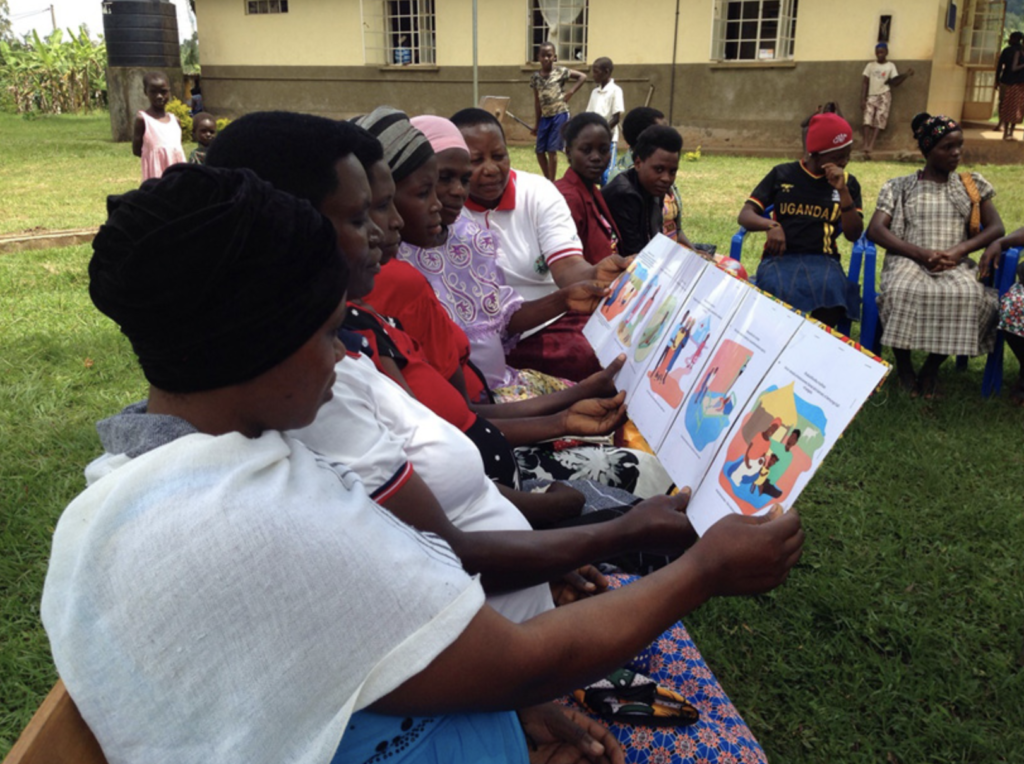 Las mujeres examinan tarjetas que muestran información médica durante una sesión del club de embarazo en el este de Uganda, crédito de la foto Kate Ramsey.