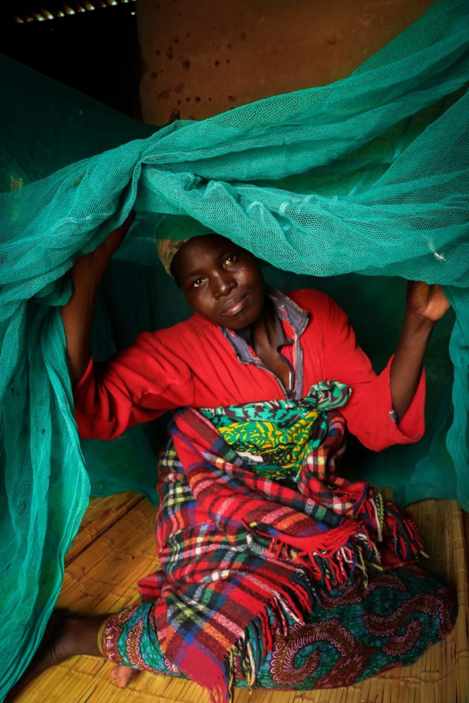 Woman under mosquito net over bed