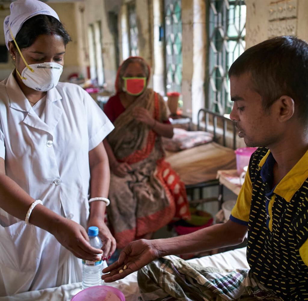 Uma enfermeira administra o tratamento de TB a um paciente