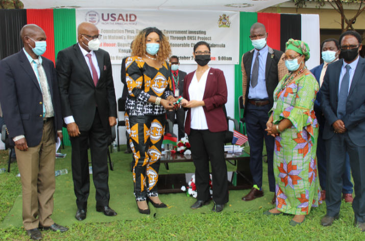 [USAID's Acting Mission Director in Malawi hands over the keys to a prefabricated family planning clinic to Malawi's Deputy Minister of Health.]