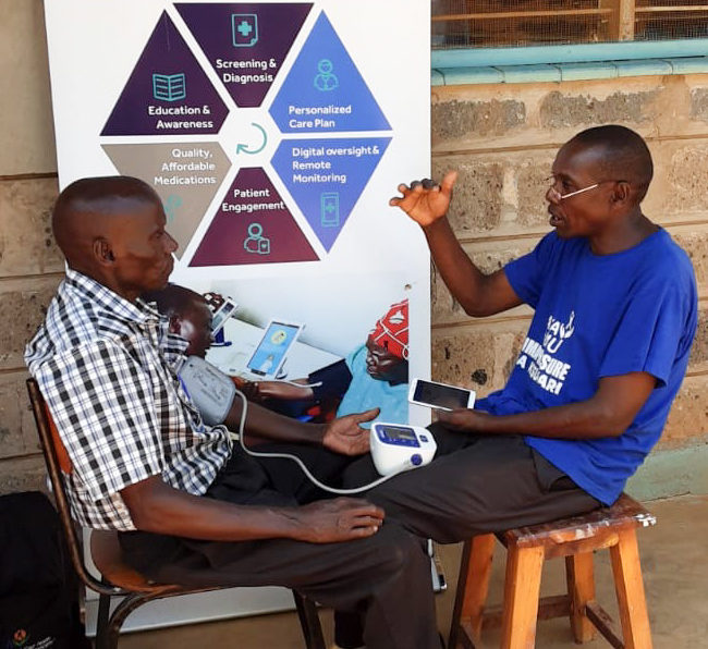 A community health volunteer visits with a patient in Makueni