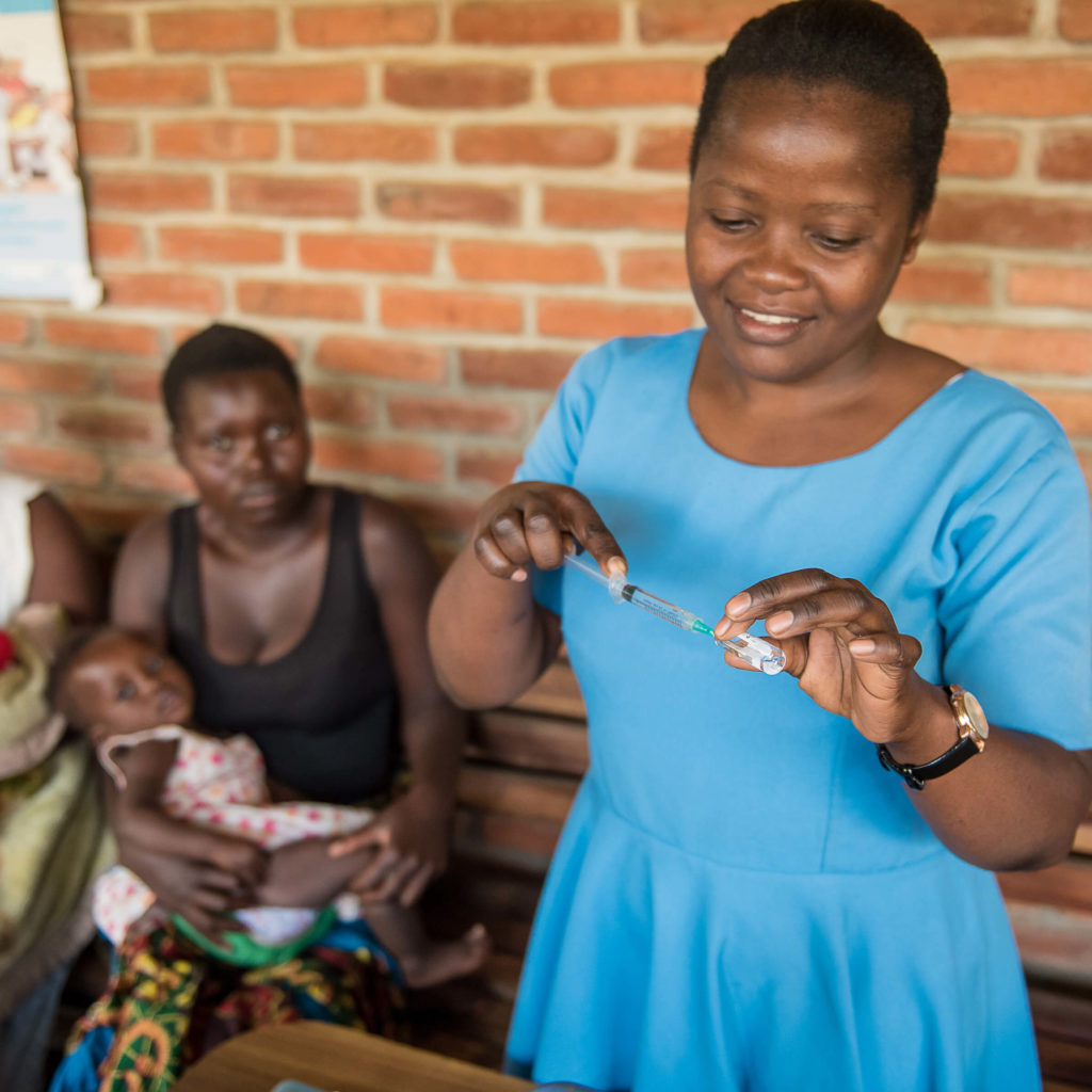 Nurse in Malawi prepares vaccine for a child