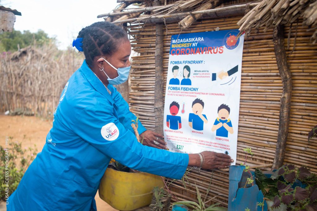 Trabajador de la salud comunitaria en Madagascar coloca un cartel educativo sobre la prevención del COVID-19.