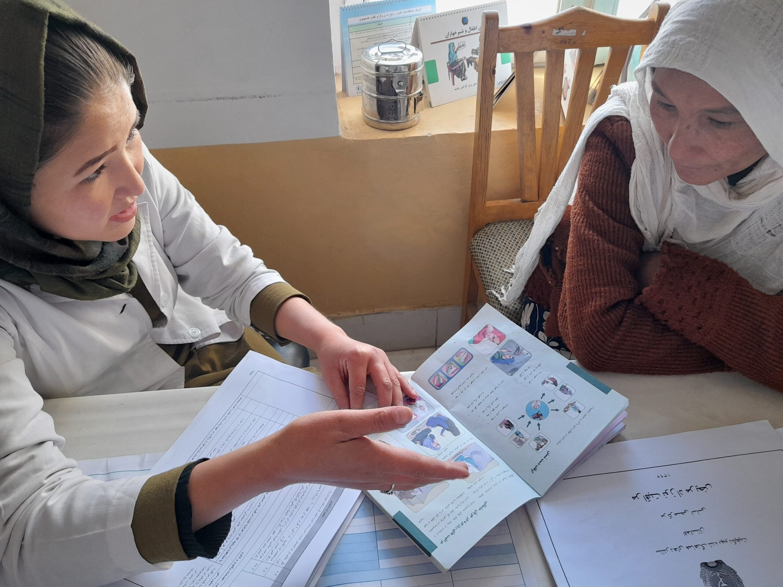 A midwife while explaining the MCH handbook to client in a local BHC covered by AFIAT. Photo by AFIAT