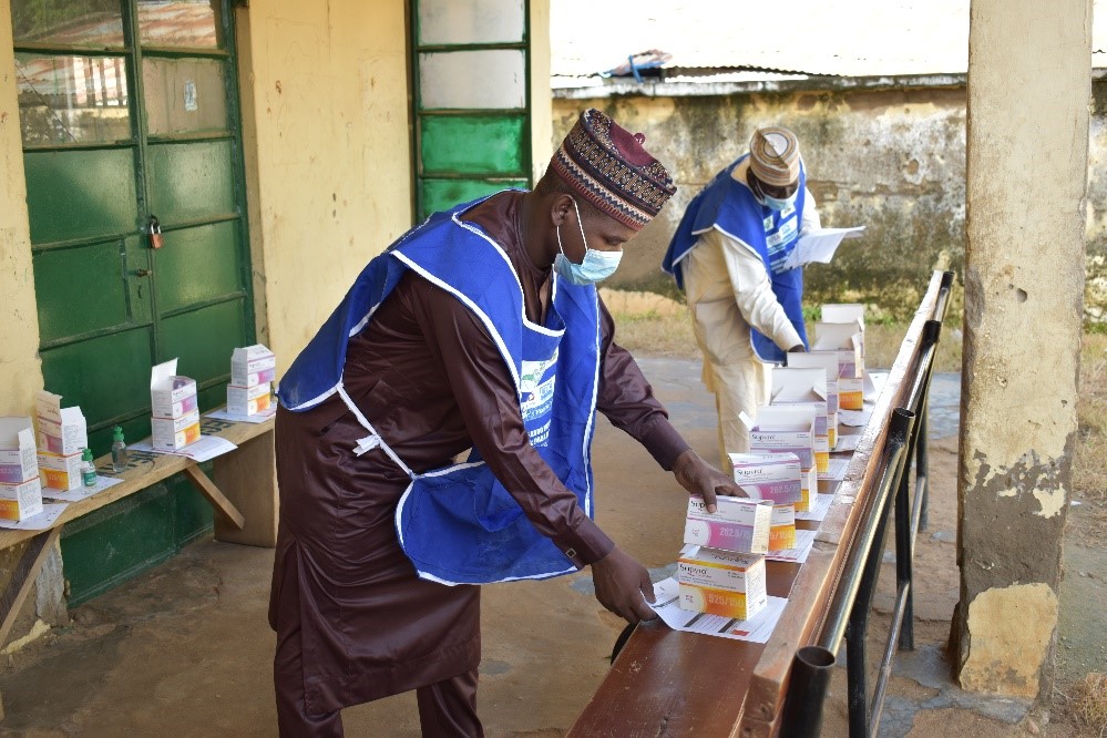 A community health volunteer picking up supplies during a seasonal malaria chemoprevention campaign in Nigeria