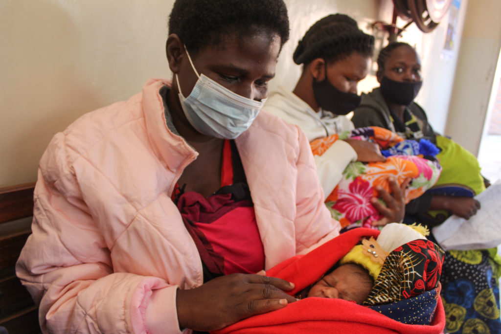 As mulheres sentam-se com seus recém-nascidos em uma clínica.