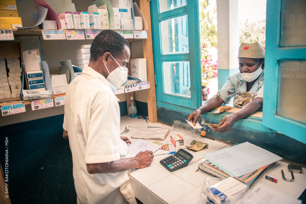 A pharmacist dispenses medication to a patient,