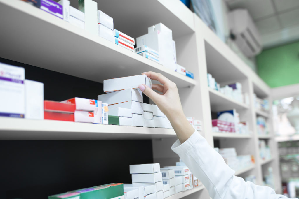 A pharmacist takes a medication off a shelf.