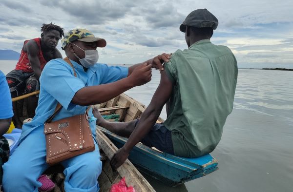 Um profissional de saúde administra uma injeção de COVID a um pescador em seu barco.