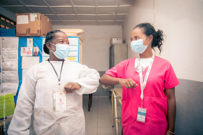 Two health workers bump elbows in solidarity.