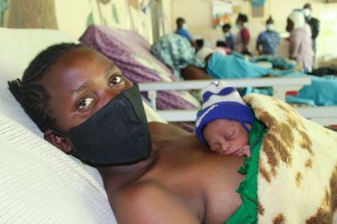 Eine Mutter mit ihrem Neugeborenen, das auf ihrer Brust ruht.