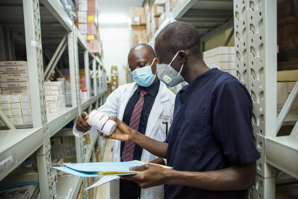Two pharmacists in a stock room examine a bottle.