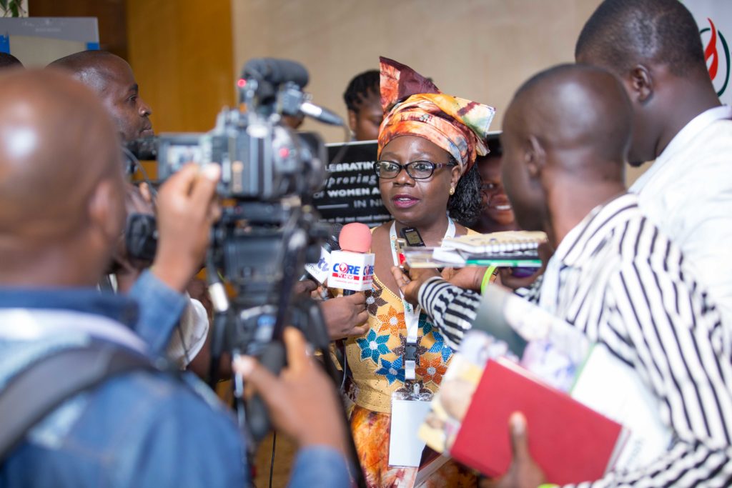 A Nigerian woman is surrounded by reporters.