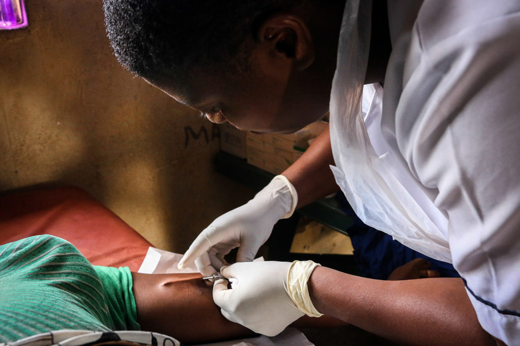 This image is a closeup shot of a health worker inserting an IUD into the arm of a women.