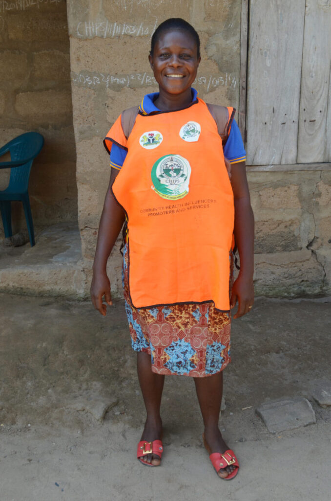A agente comunitária de saúde nigeriana Nneamaka Nwanka sorri em seu avental de trabalho com a marca PMI-S. Crédito da foto: atividade da Iniciativa contra a Malária para Estados (PMI-S) do presidente dos EUA