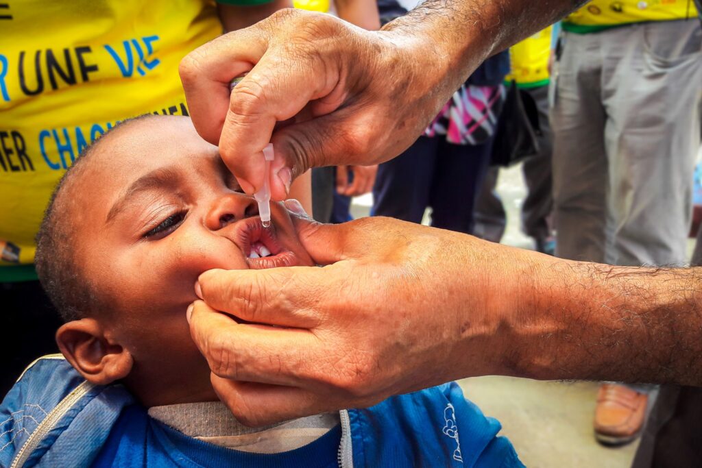 This is a closeup image of a small child having an oral vaccine administered by dropper.
