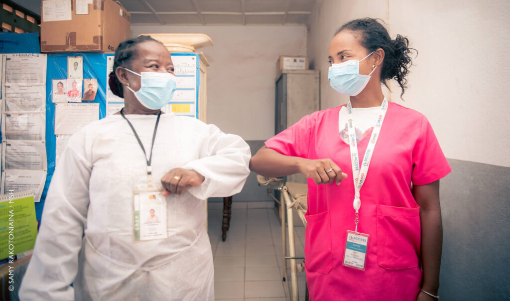 Two health workers bumping elbow.