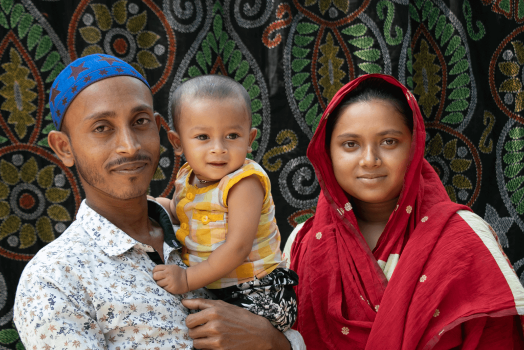 A woman, Shimla, poses for a photo with her husband, who holds their one-year-old son in Bangladesh.