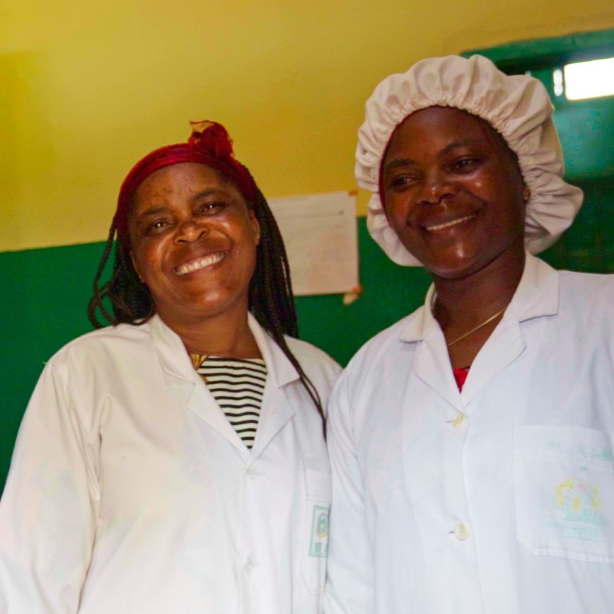 Dos farmacéuticos en Camerún se ríen juntos en un almacén frente a estantes de productos médicos.