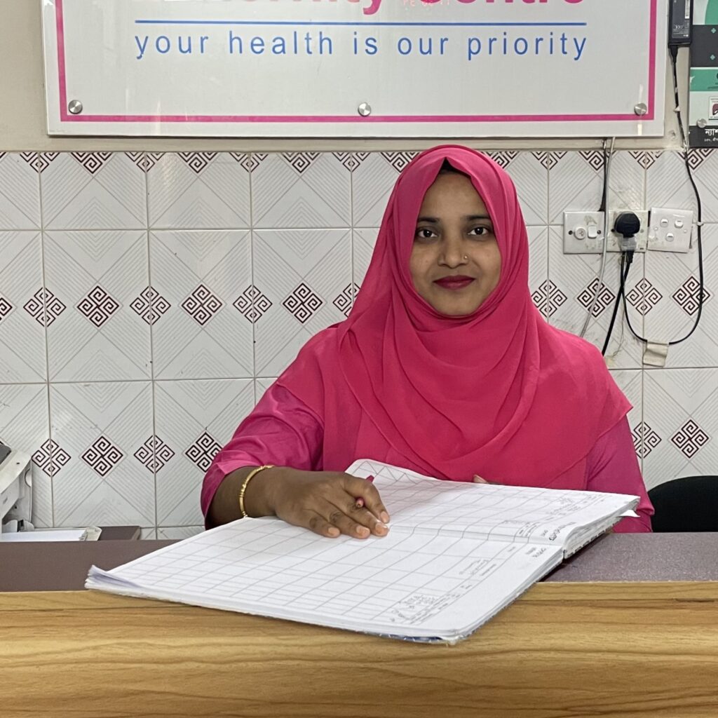 Mukta, a midwife in Bangladesh, goes over paperwork at Morkun Maternity Center's reception desk