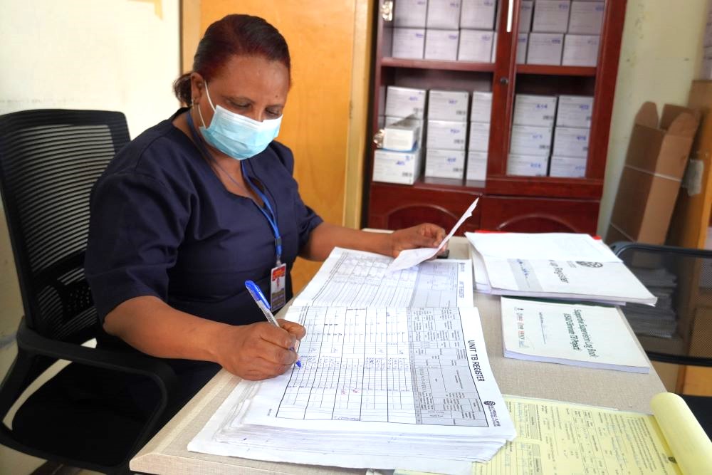 A enfermeira regista o peso de Danchile e outras informações básicas no registo de pacientes da clínica de TB. Crédito da foto: Jenn Gardella/MSH
