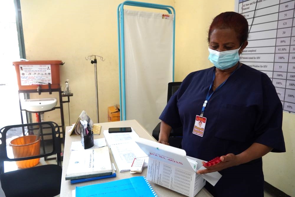 Die Krankenschwester holt Danchiles wöchentliche Medikamentendosis aus ihrem „Stop TB Patient Kit“. Bildnachweis: Jenn Gardella/MSH
