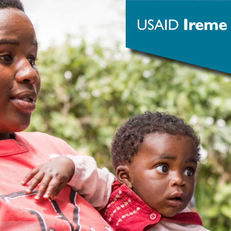 A woman holds a small child. Both are looking toward the right of the photo. The Words USAID Ireme appear in the upper right hand corner.