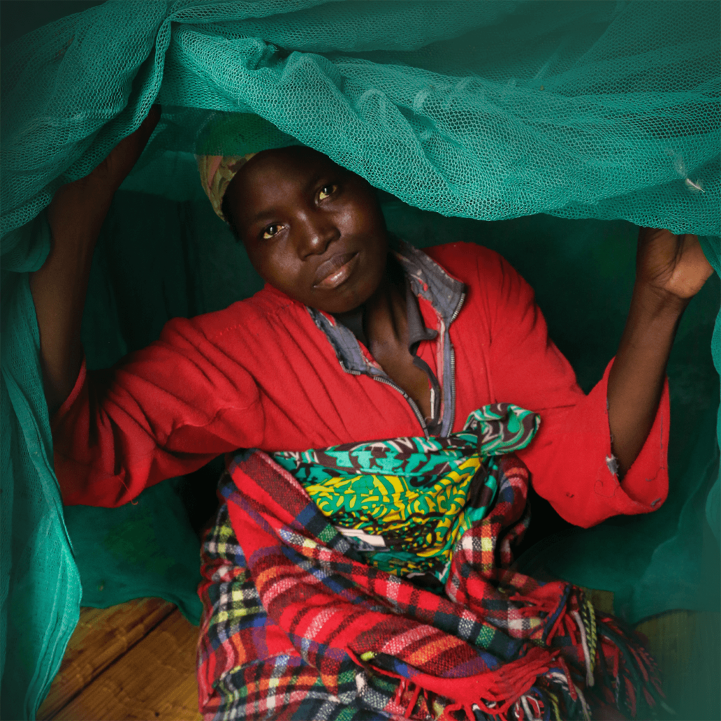 Imagen del banner del seminario web del Día Mundial de la Malaria. Una mujer vestida de rojo con una colorida panya atada alrededor de sus desechos mira desde debajo de una mosquitera verde