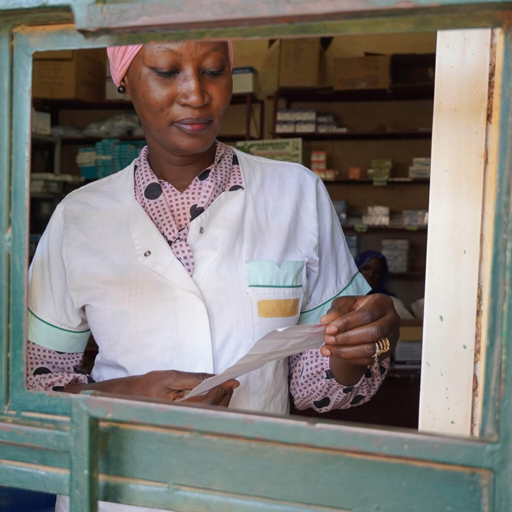 A female pharmacist in a window dispensing medication.