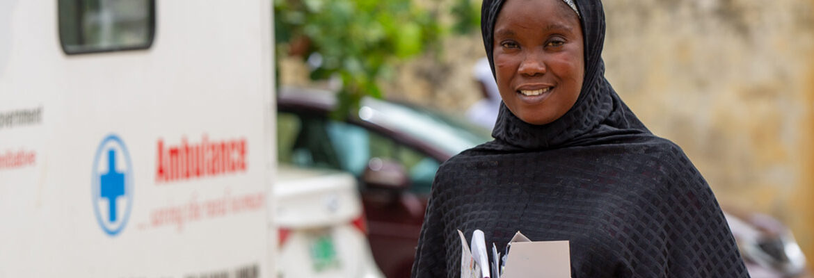A woman holding medicines standing by an ambulance
