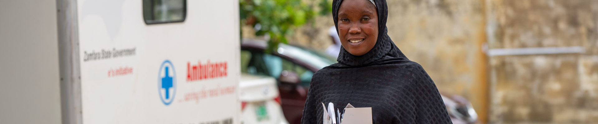 A woman holding medicines standing by an ambulance