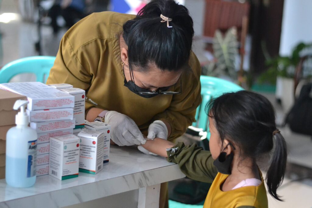 A health worker conducts a TB skin test on a young girl.