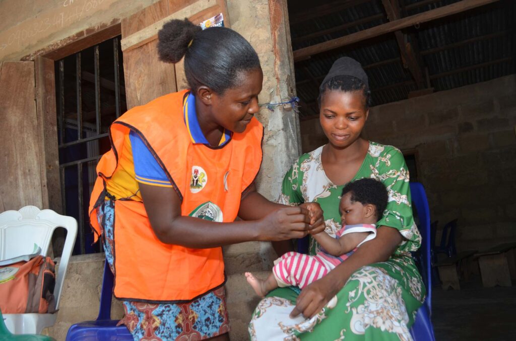 A health worker attending to a baby on her mother's lap.