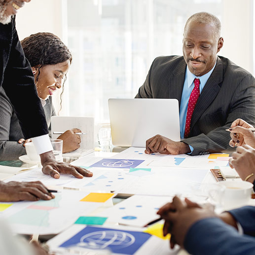 A group of people meeting and working on their laptops.