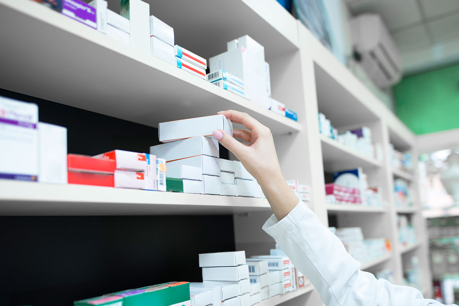 A pharmacist's hand reaching for a box od medicine