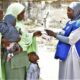 Mother receiving seasonal malaria medications for her children from a health worker in Nigeria.