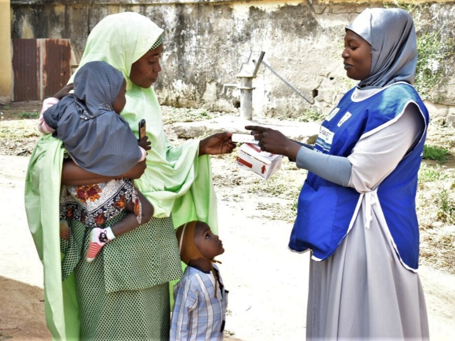 Mother receiving seasonal malaria medications for her children from a health worker in Nigeria.